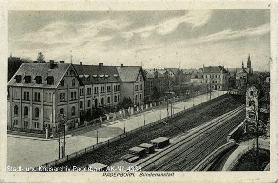 Schwarz-Weiß-Aufnahme von erhöhtem Standpunkt, links die Stadthäuser und rechts Bahngleise