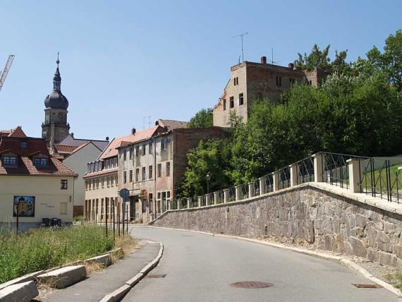 Die Mauer führt an der Straße entlang auf Wohnhäuser zu.