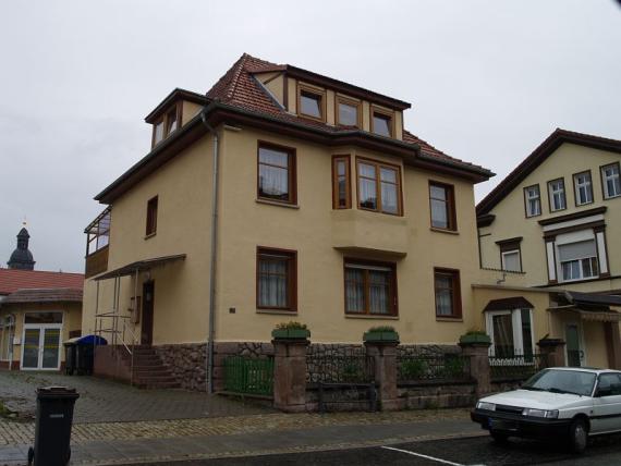 zweigeschossiges, unterkellertes, gelb verputztes Haus mit nahezu quadratischer Grundfläche