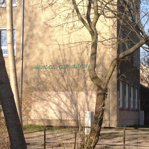 Der grüne Schriftzug "Mendel-Grundschule" ist an dem Plattenbau angebracht.
