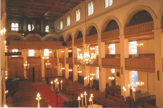 Innenraum der Synagoge. Das Kassettendach ist aus Holz sowie die Möblierung und auch die Balustraden. Über dem Eingang ist eine Orgel mit Schnitzereien.