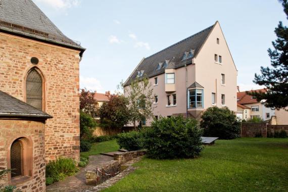 On the left a building made of red bricks, on the right a modern building with four floors
