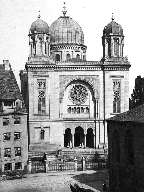 Black and white photo of the opulently decorated synagogue. Two front towers with domes and a middle, larger dome.