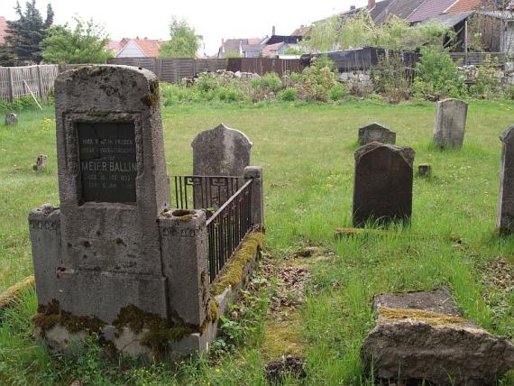 heavily weathered gravestone, grave with small stone pillars and metal grates