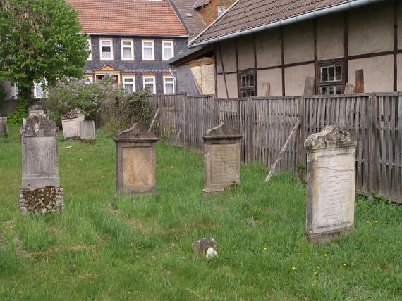 am Rand des Friedhofs: rechts ein Zaun, dahinter ein Fachwerkhaus