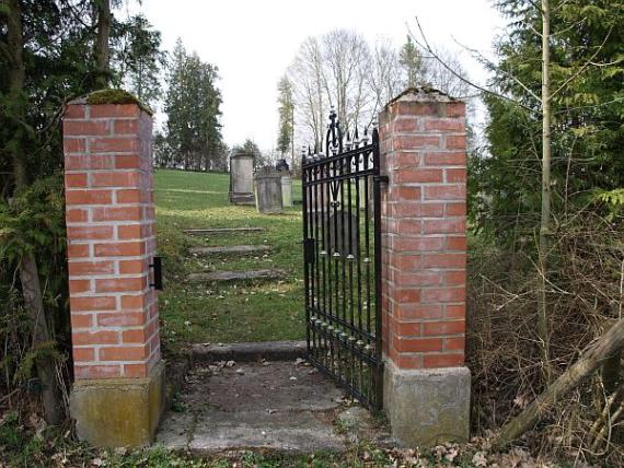 forged open entrance gate between two red brick pillars