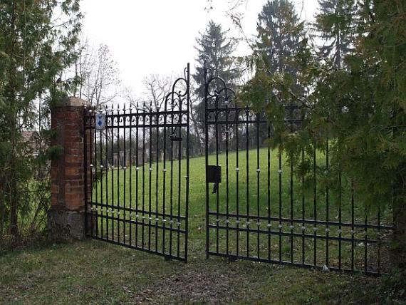 large forged gate between two red brick pillars