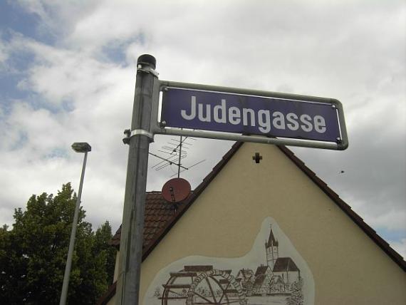 blaues Straßenschild: Judengasse, im Hintergrund ein Haus