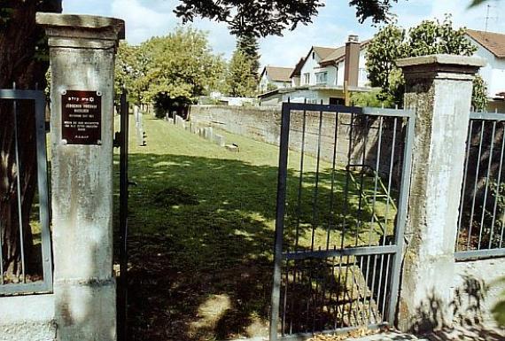 Iron gate between two pillars with a signboard on the left side