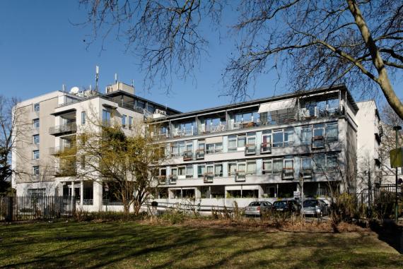 Langes, flach gedecktes Haus mit Fensterfront. Davor Rasenfläche