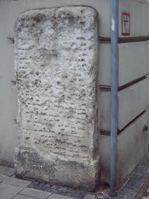 a large stone on a street corner with illegible inscription