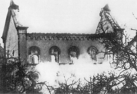 Black and white photo: outer walls still standing, in front of them a cloud of dust