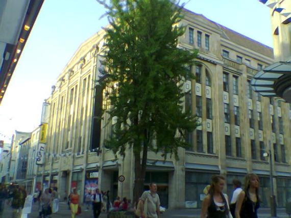 mehrstöckiges Gebäude mit vielen Fensterläden an einer Fußgängerzone