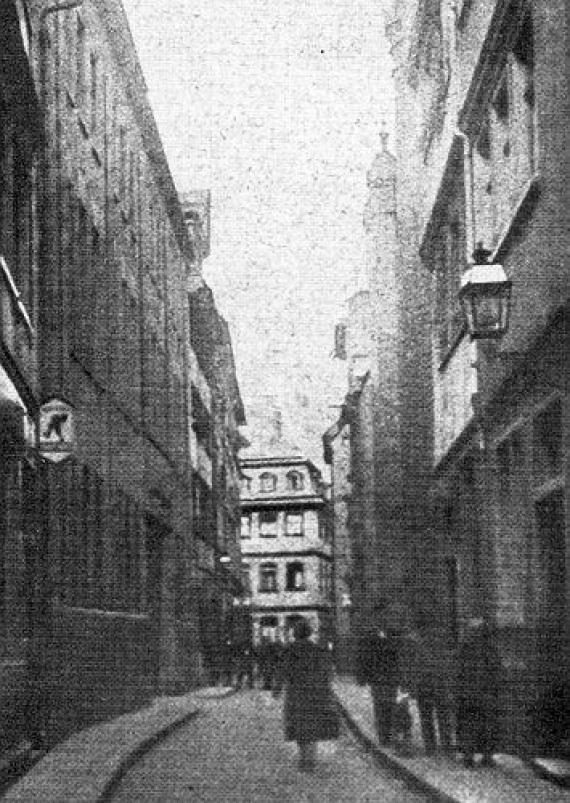 Black and white photo: narrow one lane alley with people on it