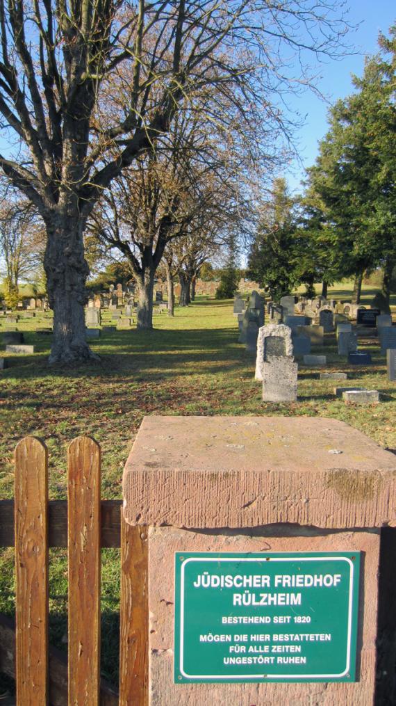 auf der Hinweistafel: "Jüdischer Friedhof Rülzheim, bestehend seit 1820. Mögen die hier Bestatteten für alle Zeiten ungestört ruhen."