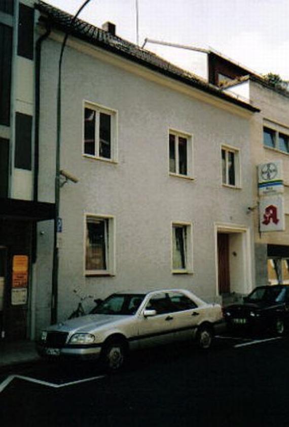 The white two-storey house with parked cars