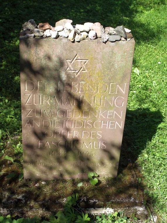 weathered memorial stone with numerous stones on it