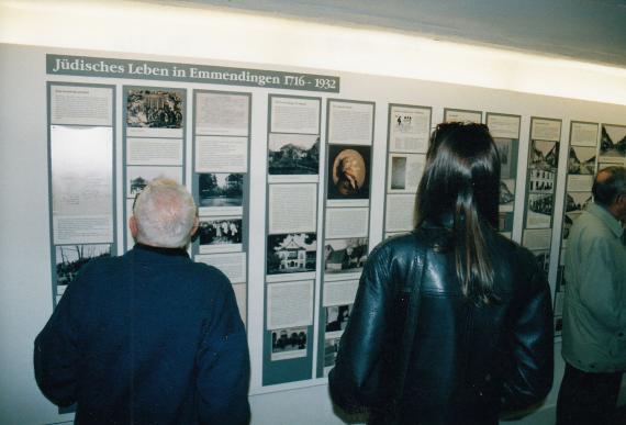 An elderly man and a woman look at display boards with text and pictures