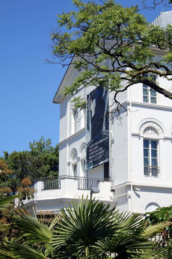 A white stately house in the green with a large terrace