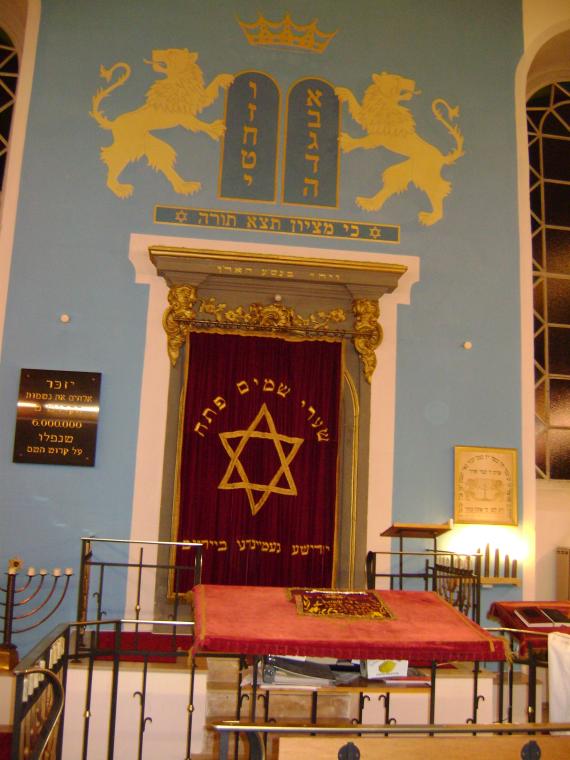 Das Innere der Synagoge mit Blick auf Tora-Schrein und Lesepult (Bima) vor der Umgestaltung 2014/18. Auf der linken Seite eine Gedenktafel für die Opfer der Schoa.