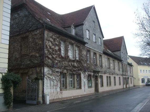 Am linken Eingang der "Alten Münze" sind noch die Spuren der früheren Nutzung durch das „Iwalewa-Haus“, das Afrikazentrum der Universität Bayreuth, zu sehen.