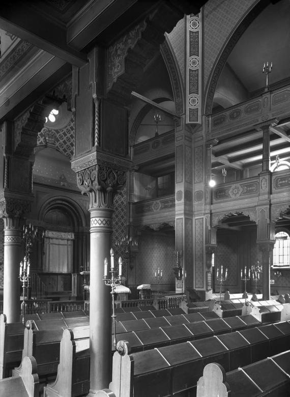 Der Innenraum der Alten Synagoge mit Holzbänken, verzierten Säulen und bogenförmiger Decke