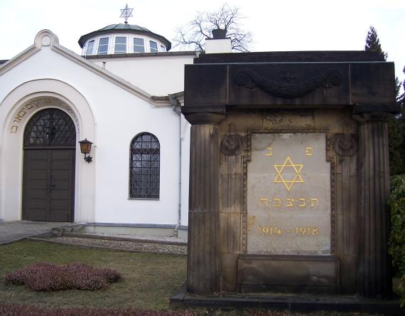 Ein großer kubischer Gedenkstein mit dorischen Säulen aufgestellt rechts der Synagoge und trägt eine Inschrift mit vergoldeten hebräischen Lettern und einem Davidstern