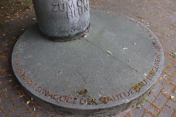 Die Sockelinschrift verweist – am falschen Ort – auf die ehemalige Synagoge: „Hier stand die Synagoge der Stadt Dessau, eingeweiht am 18.2.1908, zerstört am 9.11.1938“.