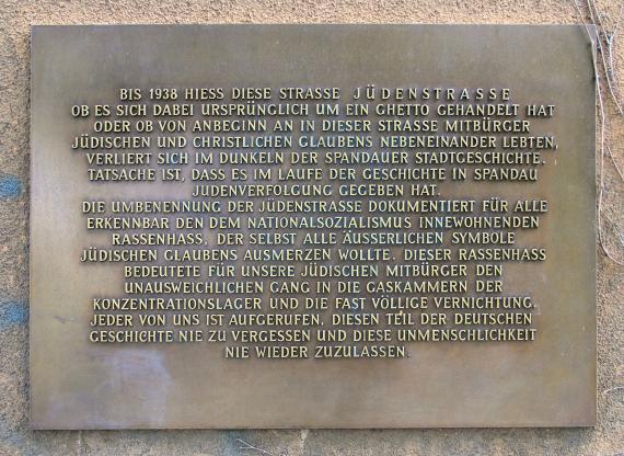Bronze memorial plaque with golden letters telling the story of the Jews and the street.