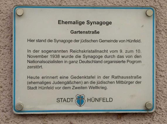 Gedenkatafel der Synagoge Hünfeld. Text: Ehemalige Synagoge Gartenstraße. Hier stand die Synagoge der jüdischen Gemeinde von Hünfeld. In der sogenannten Reichskristallnacht vom 9. zum 10. November 1938 wurde die Synagoge durch das von den Nationalsozialisten in ganz Deutschland organisiert Progrom zerstört. Heute erinnert eine Gedenktafel in der Rathausstraße (ehemaliges Judengäßchen) an die jüdischen Mitbürger der Stadt Hünfeld vor dem zweiten Weltkrieg. (Text Ende)