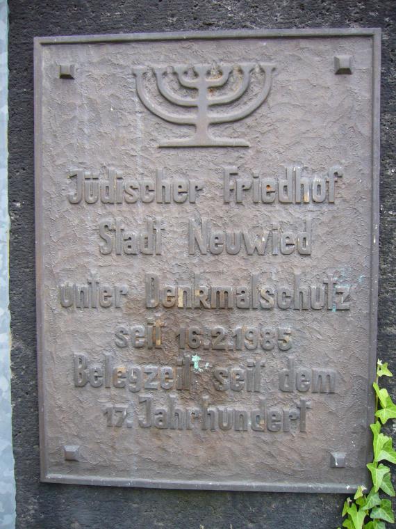 Commemorative plaque with inscription: "Jewish cemetery city Neuwied. under monument protection since 16.2.1985. occupation time since the 17th century". Above a seven-branched candelabrum