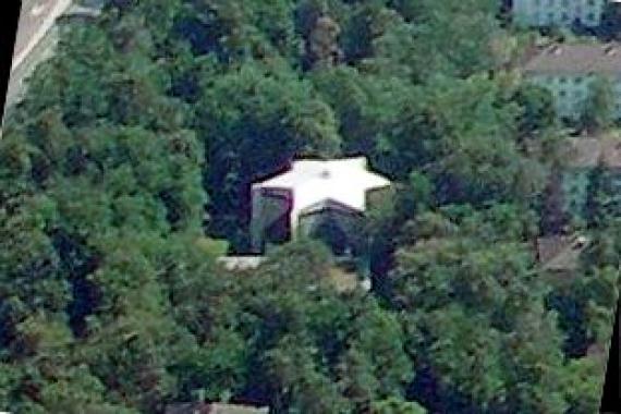 Running shot of a building located in the middle of a forest. The building has the shape of a Star of David