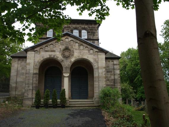 Die Friedhofshalle aus hellem Stein mit den Eingangsportalen 