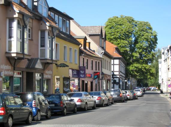 Blick auf die Jüdenstraße in Berlin-Spandau, links im Bild eine Reihe von niedrigen Häusern und Läden. Auf der Straßenseite parkende Autos