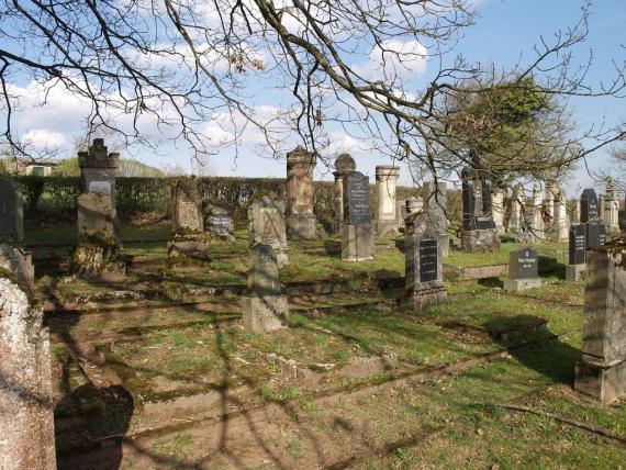 Teilansicht des Friedhofes. Hohe Grabsteine auf grünem Rasen