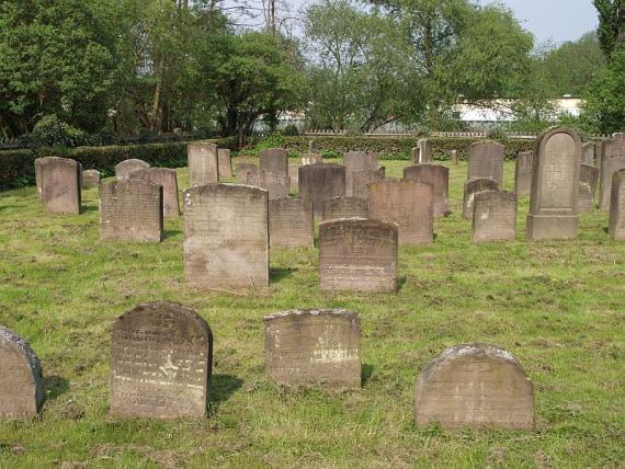 Partial view of the older area, gray-brown gravestones scattered around the yard