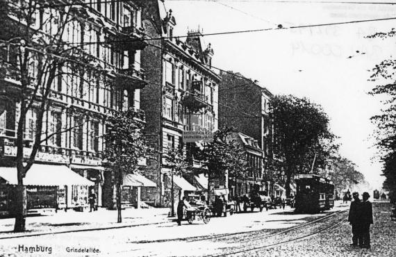 schwarz-weiß Postkarte der Grindelallee mit Häusern auf der linken Seite und in der Mitte eine Straßenbahn bei der Durchfahrt Richtung Neue Dammtor-Synagoge