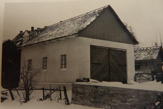 Black and white photo: simple house with big gate