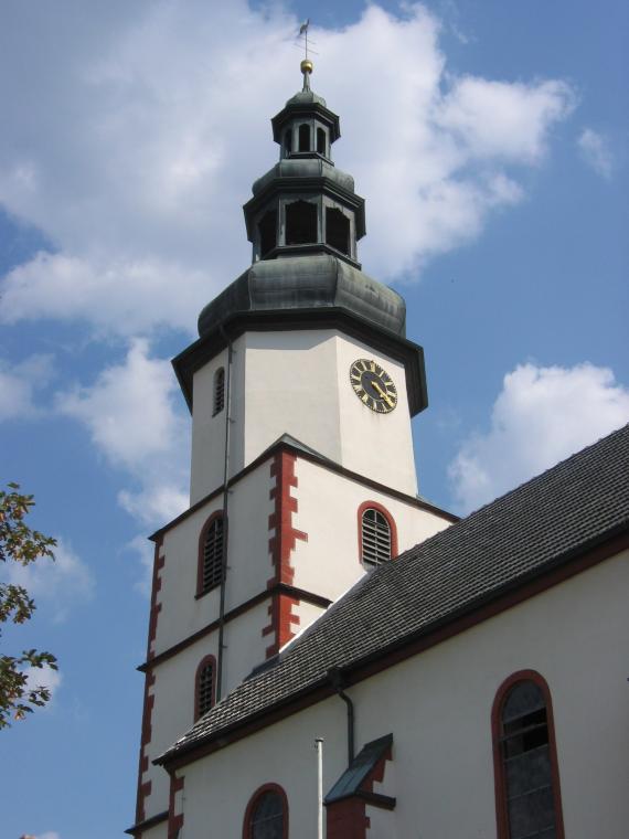 Bild der katholischen Pfarrkirche St. Vitus, weißer Bau mit Backsteineinsatz und Zwiebelturm