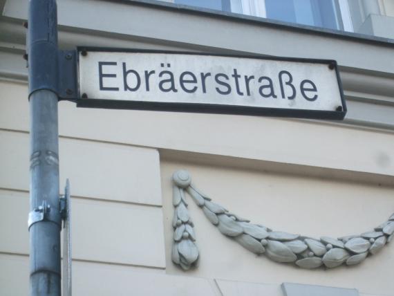 Der Eingang zur „Ebräerstraße“ befindet sich direkt gegenüber der Haltestelle „Platz der Einheit/West“. Der Name deutet auf eine jüdische Präsenz ab dem 18. Jahrhundert hin.