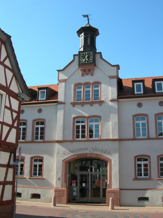 The picture shown here is of the Glöckelchen Cultural Center; a large building, a cream colored facade and brown-red details, on the tower is a large clock.