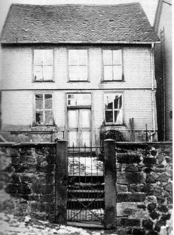 Black and white photograph half-timbered building with a gable roof and bible tail roofing