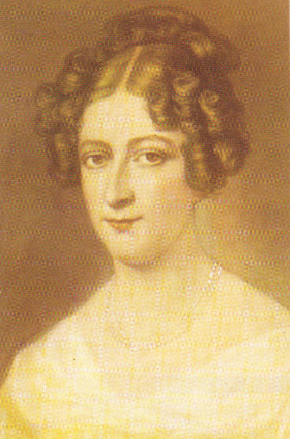Portrait of a lady with curly dark hair and eyes. She wears a chain around her neck and a white dress