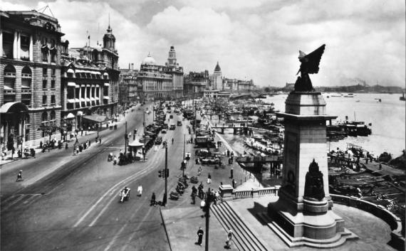 View in black and white from the port of Shanghai with a monument on the right side of the picture. On the left high buildings and between them a street