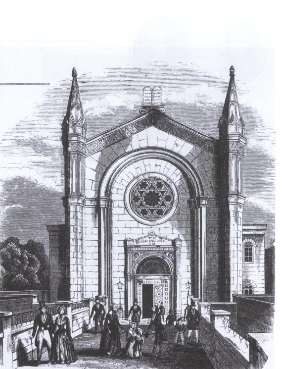 black and white wood engraving of the synagogue. Front view from a narrow street to a large house with two towers. In the center of the window is a Star of David. On the roof the tablet of the law