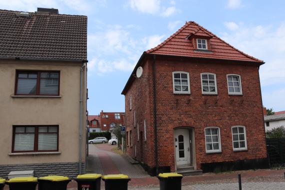 View of two houses. On the left you can see only half of a house, on the right you can see a complete house made of red brick.