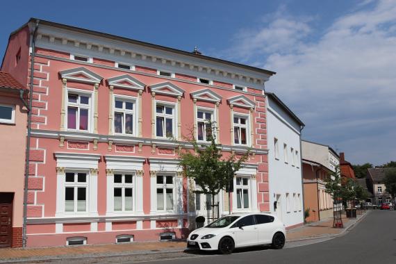 Large pink house, with a road leading off to the right.