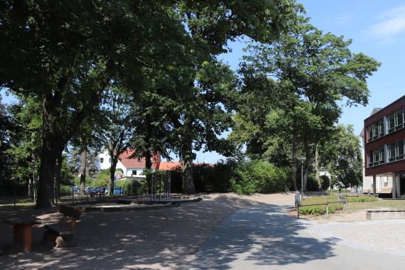 Gelände mit einem Spielplatz auf der linken Seite und einem Schulgebäude auf der rechten Seite