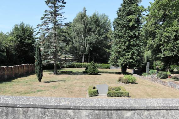 Site with individual gravestones, trees and a wall