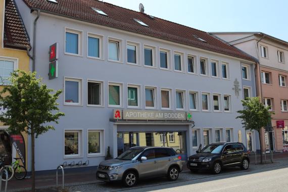 Blick auf ein langes Reihenhaus mit vielen Fenstern, im Erdgeschoss gibt es eine Apotheke